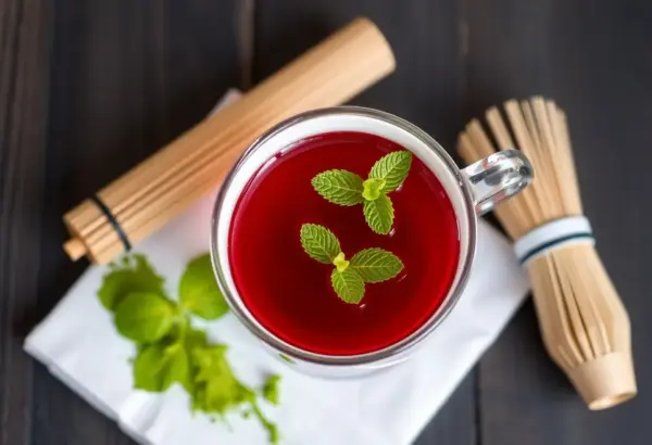 Cup of hibiscus tea with matcha tools and powder.